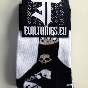May include: Black and white socks with a skull graphic. The socks have a white tag with the text "evilthings.eu" and a black and white logo.