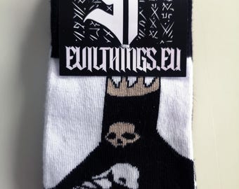 May include: A pair of white and black socks featuring a graphic of a figure wearing a crown with a skull design. The socks are attached to a black cardboard header card with a white logo and the text EVILTHINGS.EU printed in a stylized font.