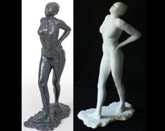 以下が含まれることがあります： 腰に手を当てて立っている裸の女性の彫刻が2つあります。左側の彫刻はブロンズ製で、右側の彫刻は白いです。