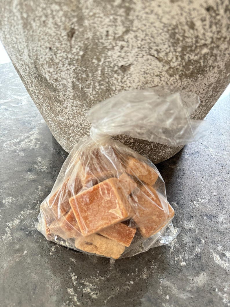 K&ouml;nnte beinhalten: Eine durchsichtige Plastikt&uuml;te gef&uuml;llt mit kleinen, quadratischen, braunen Karamellbonbons.