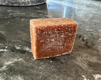 May include: A rectangular block of brown sugar with a grainy texture.