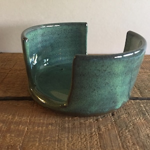 May include: A teal green ceramic dish with a unique open design. The dish is perfect for holding soap or other small items.