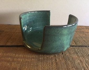 May include: A teal green ceramic dish with a unique open design. The dish is perfect for holding soap or other small items.