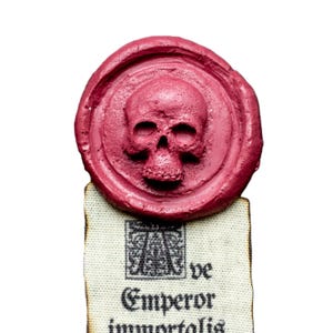 May include: A red wax seal with a skull design. The seal is on a piece of parchment paper with the text "ve Emperor immortalis".