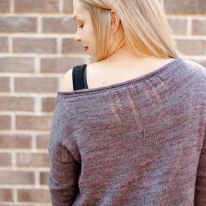 Può includere: Un maglione di lana viola e grigio con un motivo a pizzo sul retro.