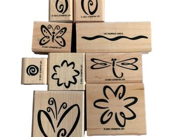 Peut inclure: Ensemble de tampons en bois avec divers motifs, dont des papillons, des fleurs, des spirales et une libellule. Les tampons sont de différentes tailles et formes, avec des motifs à l'encre noire sur un fond en bois naturel. Le texte "©2001 STAMPIN' UP!" est imprimé.