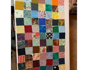 Può includere: Un blocco di trapunta a patchwork composto da 49 quadrati di tessuto diversi. I quadrati sono disposti in un motivo a griglia e presentano una varietà di colori, motivi e trame.
