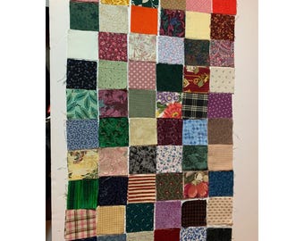 Può includere: Una trapunta patchwork realizzata con quadrati di tessuto colorati. La trapunta è composta da una varietà di motivi e colori, tra cui floreali, geometrici e paisley.