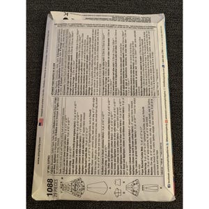 May include: A sewing pattern for doll clothes, featuring a teal satin bodice and skirt, a black velveteen bodice, and a green knit fabric for tights. The pattern includes instructions for making a cape, vest, and appliques. The pattern number is 1088 and includes 29 pieces.