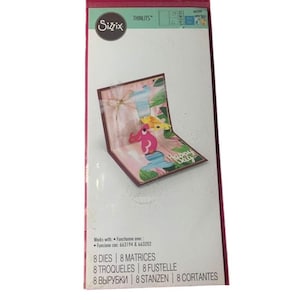 May include: Sizzix Thinlits die set for card making. The package features a pop-up card with a pink and green design, a bow, and the words "Happy Day." The package also lists the number of dies and matrices included.