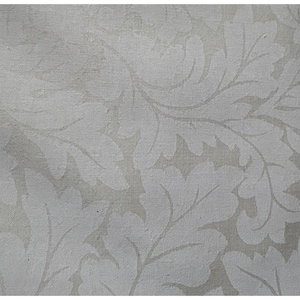 May include: A close-up of a fabric with a repeating pattern of stylized leaves and vines in shades of white and light gray. The design has a textured appearance, suggesting a woven material. The overall aesthetic is classic and elegant.
