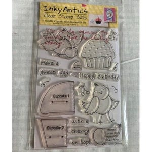 May include: Clear stamp set by Inky Antics featuring cupcake and bird designs. Includes stamps with text: "Have a great day", "Happy Birthday", and "with a cherry on top!" The set also includes cupcake and cherry illustrations.