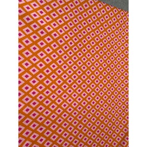 May include: Close-up of a fabric with a repeating pattern of small, white squares inside larger, orange squares. The orange squares are arranged in a diagonal grid, with pink diamond shapes in the center of each orange square.