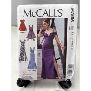 May include: McCall's sewing pattern for formal dresses. The pattern features illustrations of various dress designs, including a red strapless gown, a purple V-neck dress, and a blue gown with a slit. The pattern size is E5 (14-16-18-20-22).