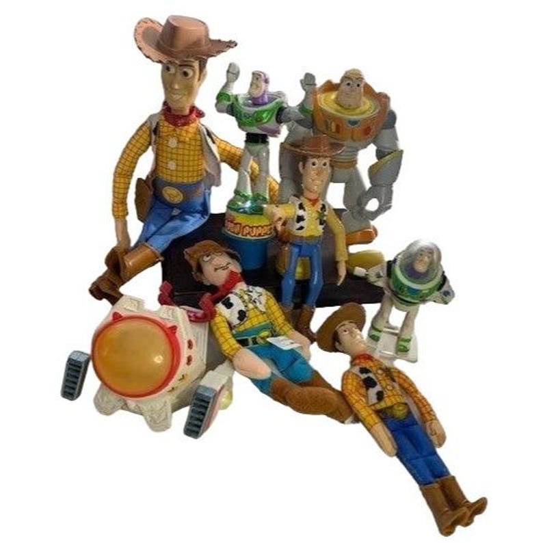 May include: A collection of Toy Story character figurines, including Woody, Buzz Lightyear, and others. The figures are in various poses and sizes, with detailed paint and design. The toys are made of plastic and are set against a white background.