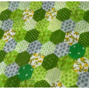 May include: A fabric featuring a repeating hexagonal pattern in various shades of green, white, and gray. The hexagons contain diverse small-scale prints, including floral motifs, dots, and textured geometric designs arranged in a quilt-like layout.