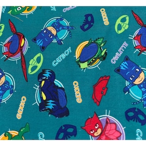 May include: Teal fabric featuring a repeating pattern of cartoon characters, including Catboy, Gekko, and Owlette. The design incorporates character names and vehicle illustrations in various colors, such as blue, green, and red. The fabric is suitable for children's crafts and apparel.
