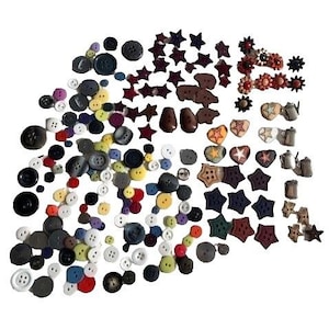 May include: A collection of various buttons in different shapes, sizes, and colors. The assortment includes round, star, and heart-shaped buttons in shades of black, white, red, yellow, and blue. Some buttons have multiple holes.