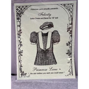 Könnte beinhalten: Illustration eines Matrosenkleides und eines Baretts für eine Puppe. Das Kleid hat einen weißen Kragen und eine Schleife, und das Barett ist gemustert. Der Text lautet "Felicity Sailor Dress and Beret for 18" doll" und "Primrose Lane".