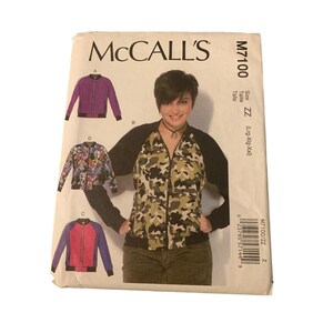 May include: A sewing pattern for a zippered jacket with a black, purple, and pink color scheme. The pattern is for sizes large, extra large, and extra extra large. The pattern number is M7100/ZZ.