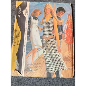 May include: A vintage McCall's sewing pattern for a dress with a houndstooth pattern. The pattern is for misses sizes 8-16 and has a bust measurement of 31 1/2 inches. The pattern is titled "Belk's Depth's Thinner Pattern" and has the number 2807 printed on it.