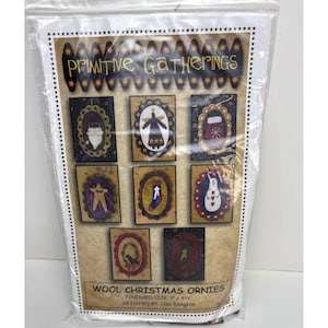May include: A package of wool Christmas ornaments with the text "Primitive Gatherings." The ornaments feature various holiday-themed designs, including a snowman, angel, and star. Finished size is 3" x 4 1/4".