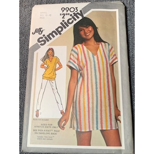 May include: Vintage Simplicity sewing pattern 9903. The pattern features a woman wearing a vertically striped tunic dress with a V-neck. The pattern also shows a yellow top and white pants. The text on the pattern reads "Jiffy Simplicity".