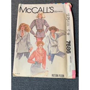 May include: A vintage McCall's sewing pattern envelope showing blouse designs. The envelope is white with the McCall's logo and pattern number 7686. The illustrations showcase different blouse styles, including a pink ruffled blouse and a plaid top.