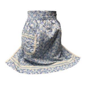 May include: A light blue floral print apron with a pocket. The apron features a repeating pattern of small blue and white flowers on a light blue background. The edges are trimmed with a white and light blue scalloped border.