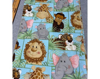 Puede incluir: Una tela azul claro con un patrón repetido de animales de dibujos animados sonrientes. El diseño incluye leones, elefantes, jirafas, tigres, monos e hipopótamos, sobre un fondo de follaje verde.