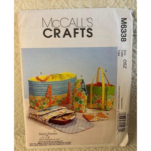 May include: McCall's Crafts sewing pattern M6338 featuring various tote bags and accessories. The pattern includes instructions for a wine bottle carrier, a casserole carrier, and other items. The designs feature orange and green fruit patterns.