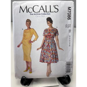 May include: McCall's sewing pattern M7086 from The Archive Collection, circa 1963. The pattern features two dress designs. One is a yellow, long-sleeved dress with a peplum. The other is a floral print dress with short sleeves. Size B5 (8-10-12-14-16).