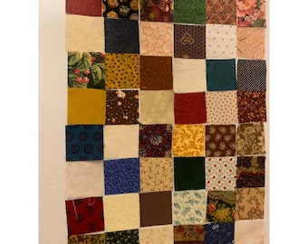 Può includere: Un blocco di trapunta a patchwork composto da 36 quadrati di tessuto in vari colori e motivi, tra cui motivi floreali, geometrici e paisley.