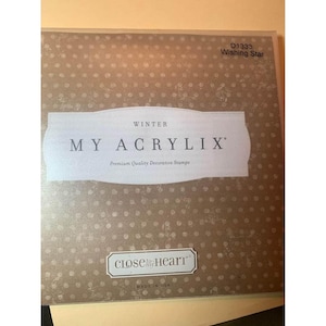 May include: A decorative stamp set with the text "MY ACRYLIX" and "WINTER" on the front. The stamp set is in a tan box with a dotted pattern. The text "Close to Heart" and "MADE IN USA" are also visible.