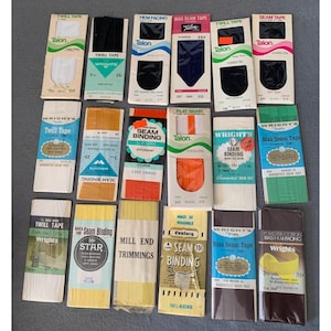 May include: Assortment of vintage sewing trims and seam binding in various colors and brands, including Talon, Wright's, Star, Century, and Mill End. The trims are packaged in small cardboard boxes with labels indicating their type, size, and color.
