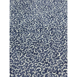 May include: Close-up of a fabric with a repeating pattern of white, swirling, vine-like designs on a dark blue background. The fabric has a textured appearance, with the white designs contrasting against the deep blue.