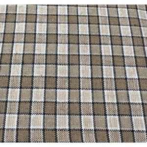 May include: Close-up of a woven fabric with a classic plaid pattern. The design features a grid of alternating squares in shades of tan, brown, black, and white. The fabric has a textured appearance.