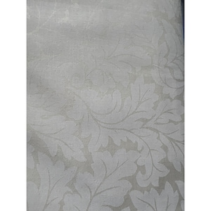 May include: Close-up of a fabric with a repeating pattern of stylized leaves in a light gray color. The leaves have a detailed, textured appearance, creating a subtle contrast against the lighter background. The fabric has a soft, muted aesthetic.