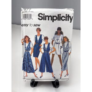 May include: A Simplicity sewing pattern packet featuring illustrations of women's clothing designs. The packet is white with the brand name "Simplicity" and the text "easy to sew". The designs include jumpsuits, dresses, and a romper.