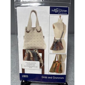 May include: A package featuring a sewing pattern for various tote bags and purses. The pattern, titled "Grids and Grommets," includes images of different bag styles, showcasing quilted designs and grommet details. The Indigo Junction logo is visible.
