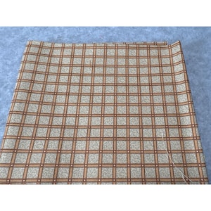 May include: A brown and beige fabric with a checkered pattern. The fabric has a subtle texture and a slightly faded look.