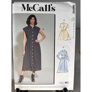 May include: McCall's sewing pattern featuring a woman in a black and white checked dress with a button-down front. The pattern includes multiple view options and is designed and printed in the USA. The size is K5 (8-10-12-14-16).