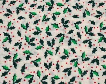 May include: Close-up of a fabric with a repeating pattern of green holly leaves and small red berries on a cream-colored background. The design is evenly spaced, creating a festive, holiday-themed textile.