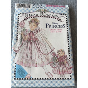 May include: A Simplicity sewing pattern envelope for a Daisy Kingdom Disney Princess child's dress and doll dress, sizes 3 to 8. The cover features an illustration of a child and a doll wearing matching white dresses with pink floral accents.