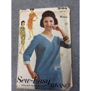 May include: Vintage sewing pattern featuring a blue dress with a V-neck and three-quarter sleeves. The pattern includes illustrations of different dress styles and the text "Sew-Easy ADVANCE". Size 14.