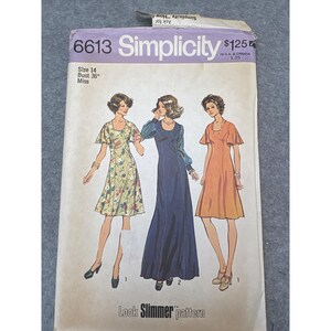 May include: Simplicity sewing pattern 6613, featuring three dress designs. The pattern cover includes illustrations of the dresses, size 14, and bust 36 inches. The text "Look Slimmer pattern" is also visible.
