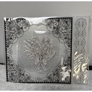 May include: Clear stamp set featuring a floral bouquet design with a bow. The stamp is surrounded by a decorative black border with floral and scroll patterns. Additional stamps with floral designs are included.