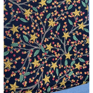 May include: A dark blue fabric with a repeating pattern of gold stars and red and orange berries. The fabric has a subtle texture and a slightly faded look.
