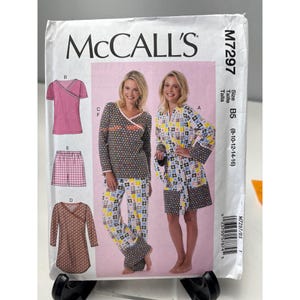 May include: McCall's sewing pattern M7297 featuring pajama sets and a robe. The pattern includes a pink wrap top, shorts, and a long-sleeved dress. The size is B5 (8-10-12-14-16).