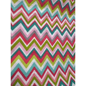 May include: A colorful fabric with a repeating chevron pattern. The zig-zag design features alternating stripes of white, pink, green, teal, and gray. The fabric is likely used for home decor or crafting projects.